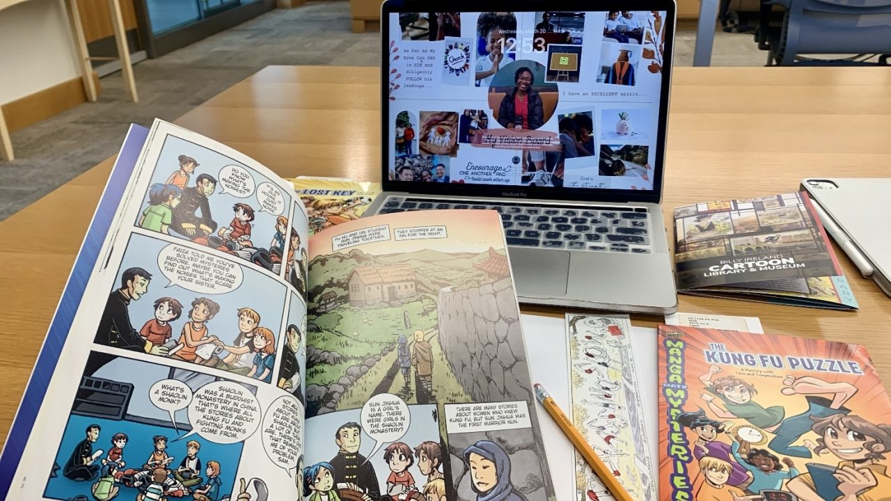 Laptop and comics on a desk displaying Ruth Oliwe's research